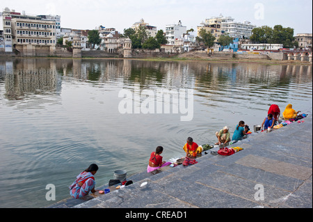 Indian women washing clothes on the shore, ghat, of Lake Pichola, Udaipur, Rajasthan, India, Asia Stock Photo