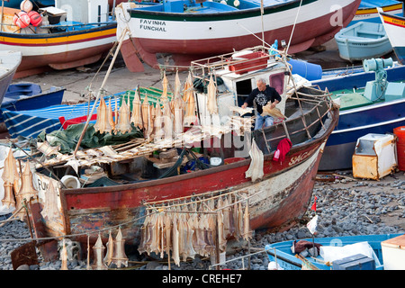 A fisherman is hanging up cod to dry in his boat, port of Camara de Lobos, Madeira, Portugal, Europe Stock Photo