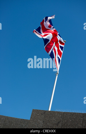 Union flag  on a flagpole flying against a blue Stock Photo