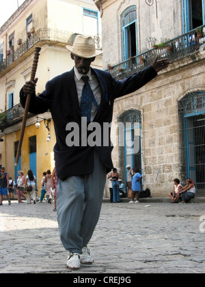 man dancing in the streets of  the old town, with stick, hat and cigar, Cuba, La Habana