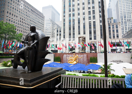 Statue at Outside the Rockefeller plaza, Center, Manhattan, New York City umbrellas of the sunken restaurant and flags of nation Stock Photo