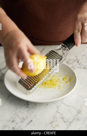 Chef grating lemon in bowl Stock Photo