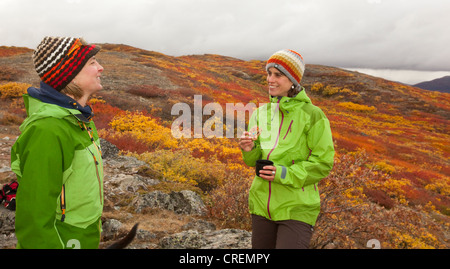 Two young women talking, laughing, sub alpine tundra, Indian summer, leaves in fall colours, autumn, near Fish Lake