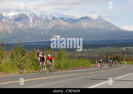 Cyclists racing in front of St. Elias mountain, at the Kluane Chilkat International Bike Relay, bicycle race from Haines Stock Photo