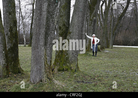 woman in a white jacket proppingagainst a tree Stock Photo