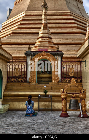 Myanmar, Burma, Yangon. Sule Pagoda. Woman Praying in front of Buddha Statue. Stock Photo