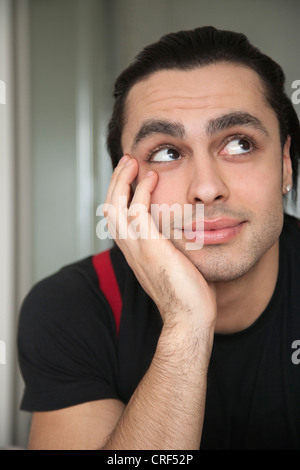 Smiling young man looking up with curiosity Stock Photo