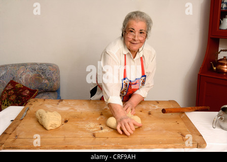 Older woman kneading dough on board Stock Photo