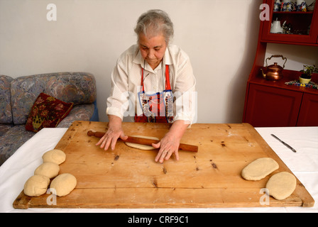 Older woman rolling dough on board Stock Photo