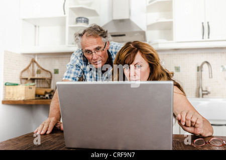 Older couple using laptop in kitchen Stock Photo
