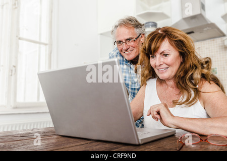Older couple using laptop in kitchen Stock Photo