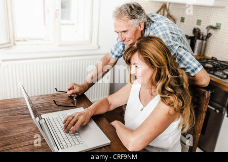 Older couple using laptop in kitchen Stock Photo