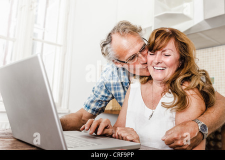 Older couple using laptop in kitchen Stock Photo