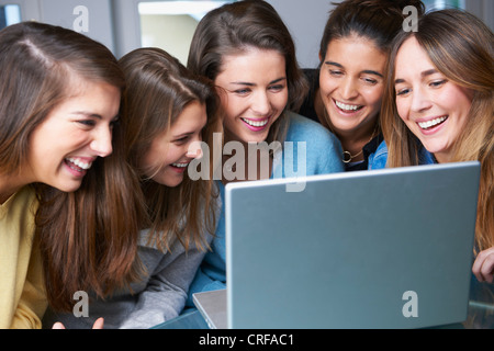 Smiling women using laptop together Stock Photo