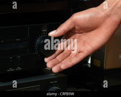 Afro-Caribbean Man's Hand Turning Volume Control Knob On A HI FI System Stock Photo