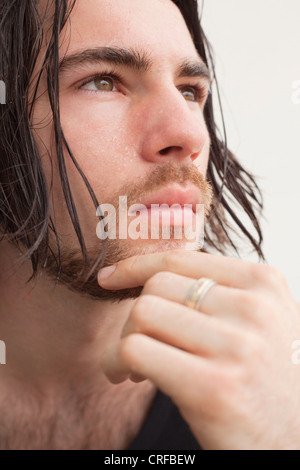 Close up of a thoughtful young man with hand on chin Stock Photo