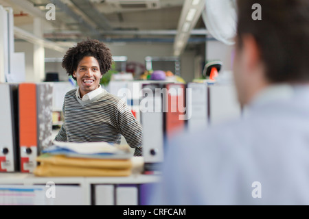 Businessmen talking at desks Stock Photo