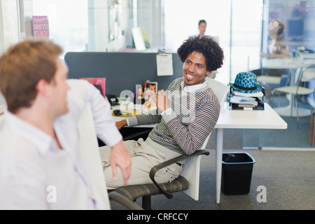 Businessmen talking at desks Stock Photo