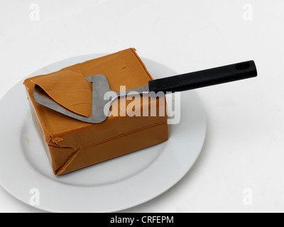 Norwegian Gjetost Brown Goats Cheese On A Plate With Cheese Slicer Stock Photo