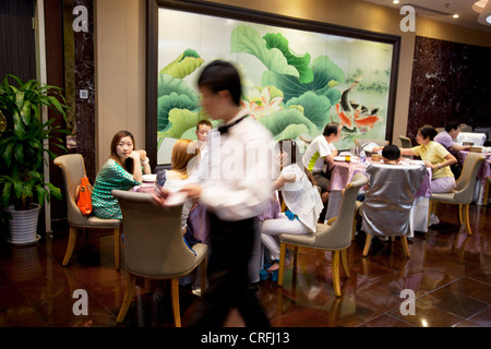 Waiting staff and customers in the main dining room. Quanjude roast duck restaurant in Wangfujing, Beijing. Stock Photo