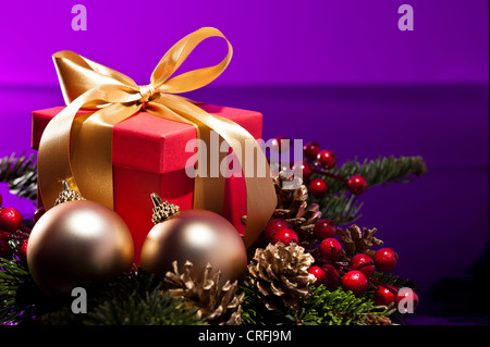 Red present box in an elegant Christmas decoration, in front of a purple background Stock Photo