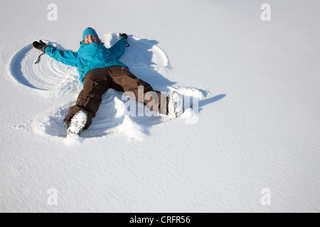 Woman making snow angel on field Stock Photo