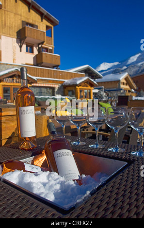 restaurant outside in Val d'Isere ski resort. Wine glasses and iced wine with snow on a table, France, Savoie Stock Photo