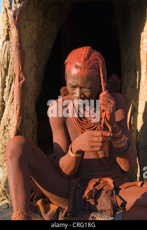 traditional Village of Purros, Himba woman dressing her hair in the morning, Namibia, Purros