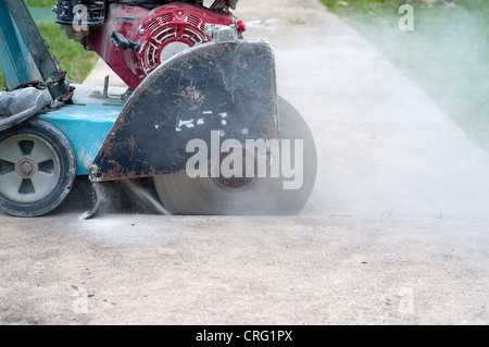 A concrete saw on a cart cutting through sidewalk Stock Photo
