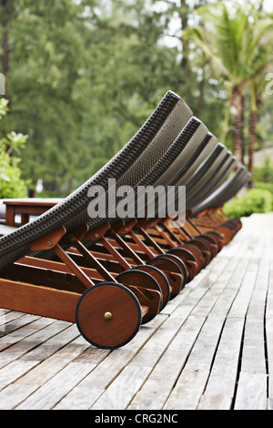 Lawn chairs lined up on wooden deck Stock Photo
