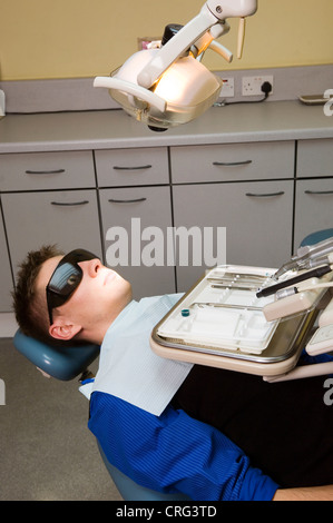 Young male patient in the dentist’s chair in front of a tray of dental instruments Stock Photo