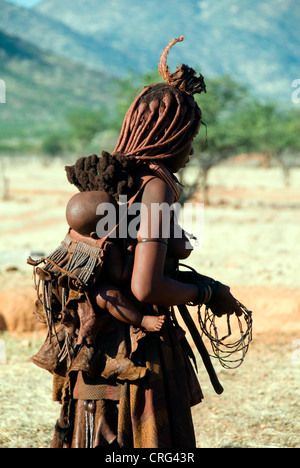 Himba woman with child on her back, Kaokoveld, Namibia Stock Photo