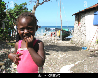 young girl from a fisher's family with a house directly on the Caribbean Sea, fisherboat in background, Haiti, Grande Anse, Dame Marie Stock Photo