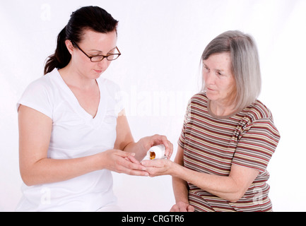 senior woman gets pills from elderly care nurse Stock Photo