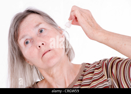 elderly woman takes ear drops Stock Photo