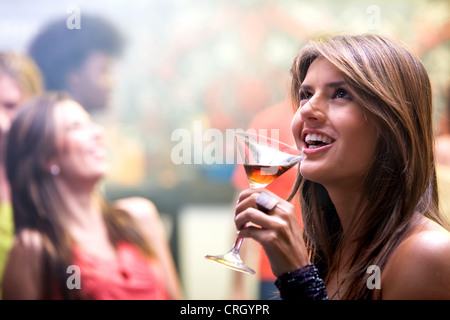 happy and smiling woman in a bar or a nightclub having a cocktail drink Stock Photo