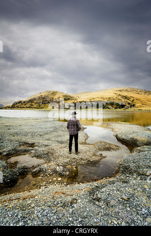 Man standing in wild scenery under a brooding sky. New Zealand, South Island. Model release available. Stock Photo
