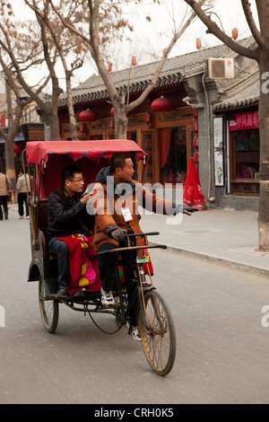 Rickshaw driver taking tourist for Hutong tour, Beijing China Asia Stock Photo