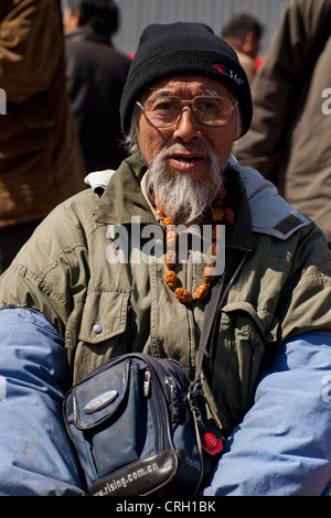 Old Chinese man wearing glasses and knit hat at Panjiayuan flea market Stock Photo