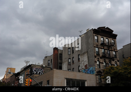 Grey sky view 5-storey brick tenements, graffiti cement render side walls, St Mark's Place at 2nd Avenue, East Village, New York Stock Photo