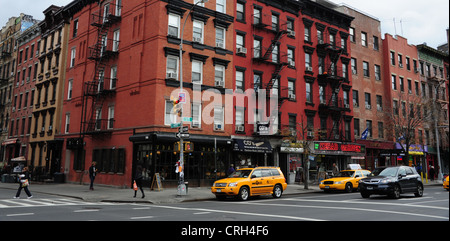 View car yellow taxis people red brick tenements Rainbow Music Store, corner 1st Avenue St.Mark's Place, East Village, New York Stock Photo