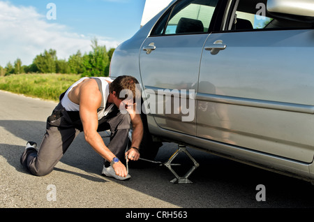 Mechanic lifting a car with jack-screw Stock Photo