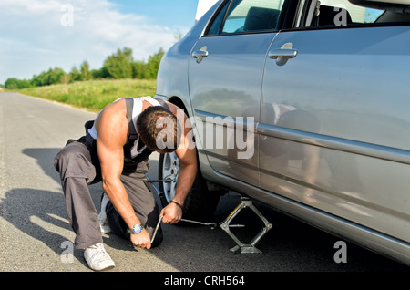 Mechanic lifting a car with jack-screw Stock Photo