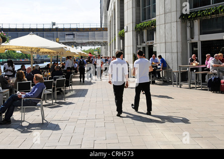 Summer sunshine eating & drinking outdoors cafe bar tables under shade from parasols Canary Wharf Isle of Dogs Tower Hamlets, East London England UK Stock Photo