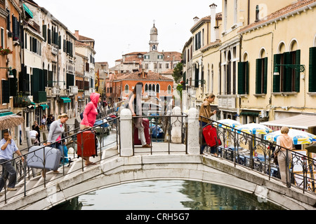 People crossing a bridge on a canal of Venice, Italy