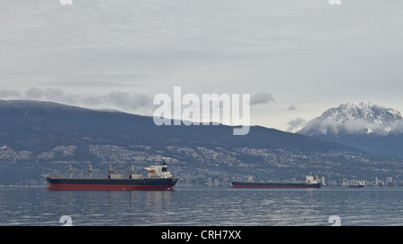 Cargo ships wait in the English Channel along North and West Vancouver's coastline on an overcast winter day. Stock Photo