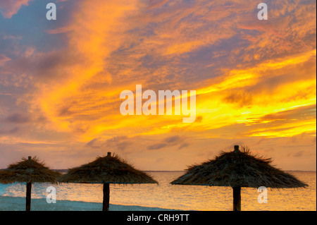 Reed umbellas on beach at sunset in Grace Bay. Providenciales. Turks and Caicos. Stock Photo