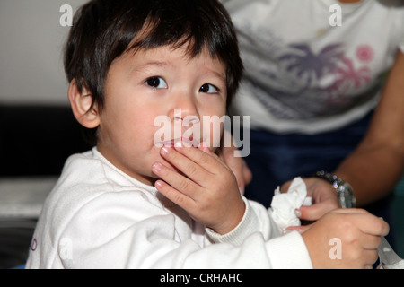 It's Chinese Eurasian baby Boy who is the center of this photo. he thinks dreams literally drinking life. He sits on wood chair Stock Photo