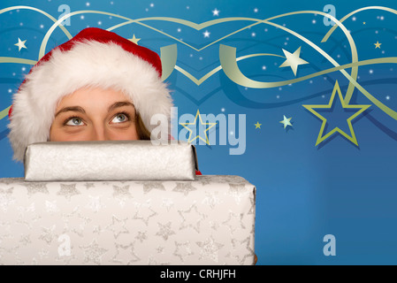 Young woman peeking over stack of Christmas gifts Stock Photo