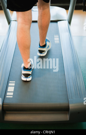 Man running on treadmill, low section, rear view Stock Photo